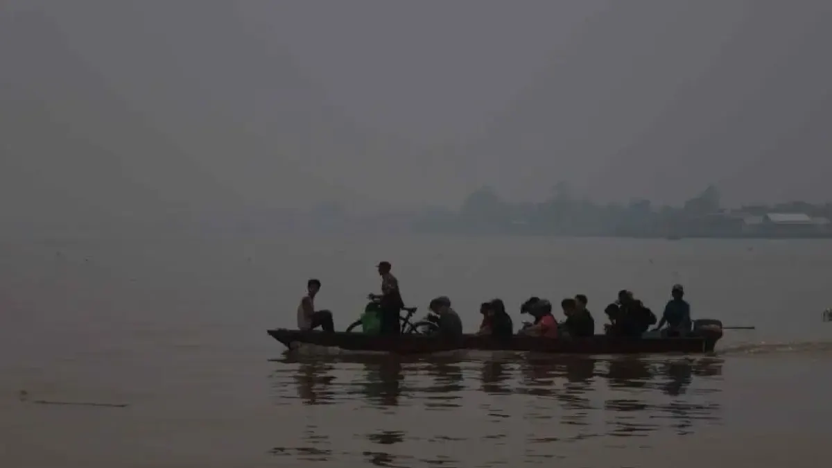 Kabut asap menyelimuti perahu motor membawa penumpang di Sungai Kapuas, Kota Pontianak pada Kamis (8/10). Kualitas udara Kota Pontianak mencapai kategori berbahaya dengan AQI 439 dan konsentrasi PM2.5 sebesar 295 µg/m³ pada Jumat (9/10) pukul 22.00 WIB. Asap berpotensi berasal dari kebakaran lokal maupun terbawa angin dari wilayah lain.